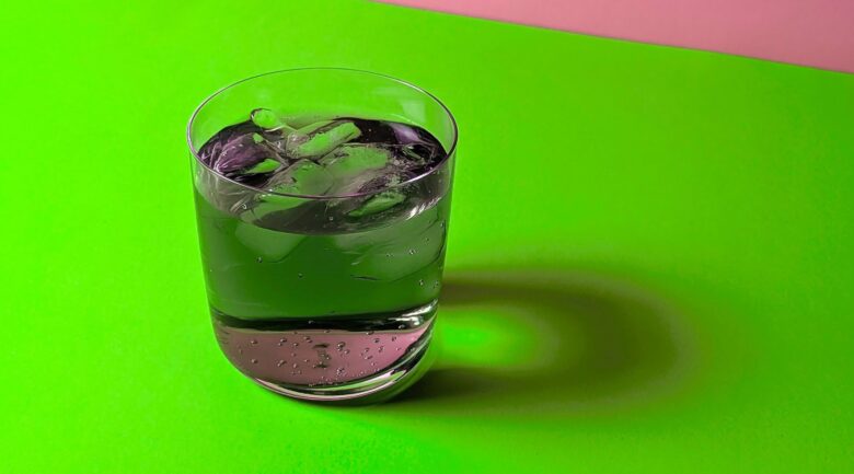 close-up of chlorophyll vodka soda drink on a pink and green background in honor of the movie 'Wicked'